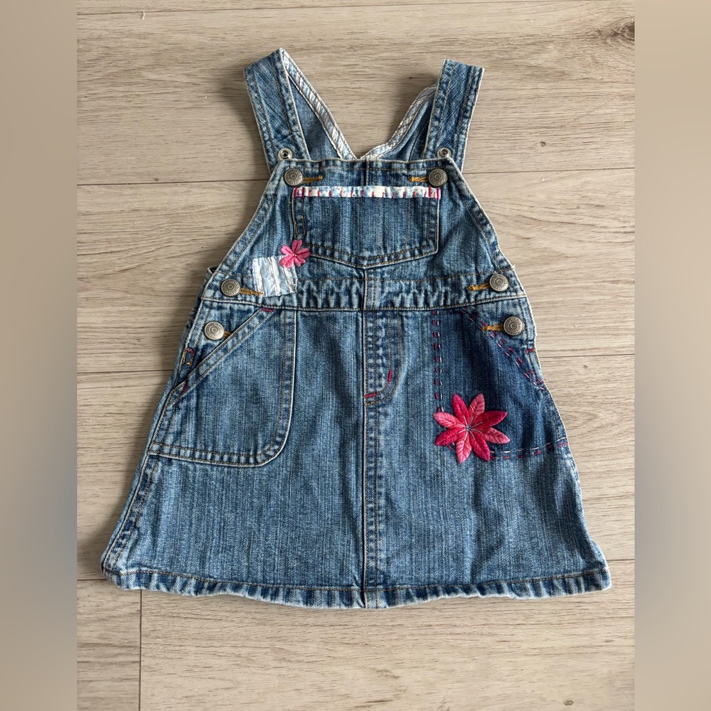Baby Gap denim jumper dress‎ featuring overall-style straps, embroidered flowers